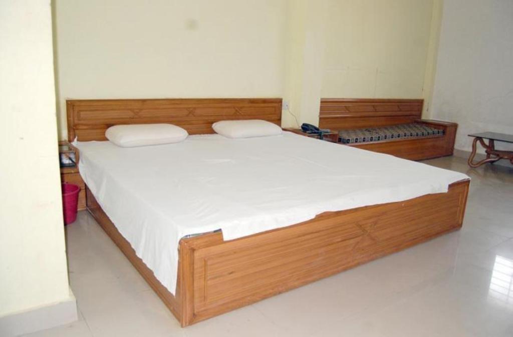 ein Schlafzimmer mit einem großen Holzbett mit weißer Bettwäsche in der Unterkunft Hotel Sambodhi International, Madhya Pradesh in Sānchi