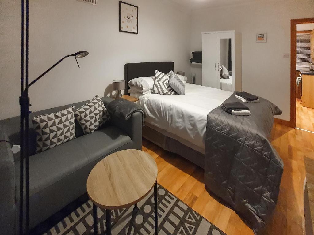 ein Schlafzimmer mit einem Bett, einem Sofa und einem Tisch in der Unterkunft Hynish House in Stornoway