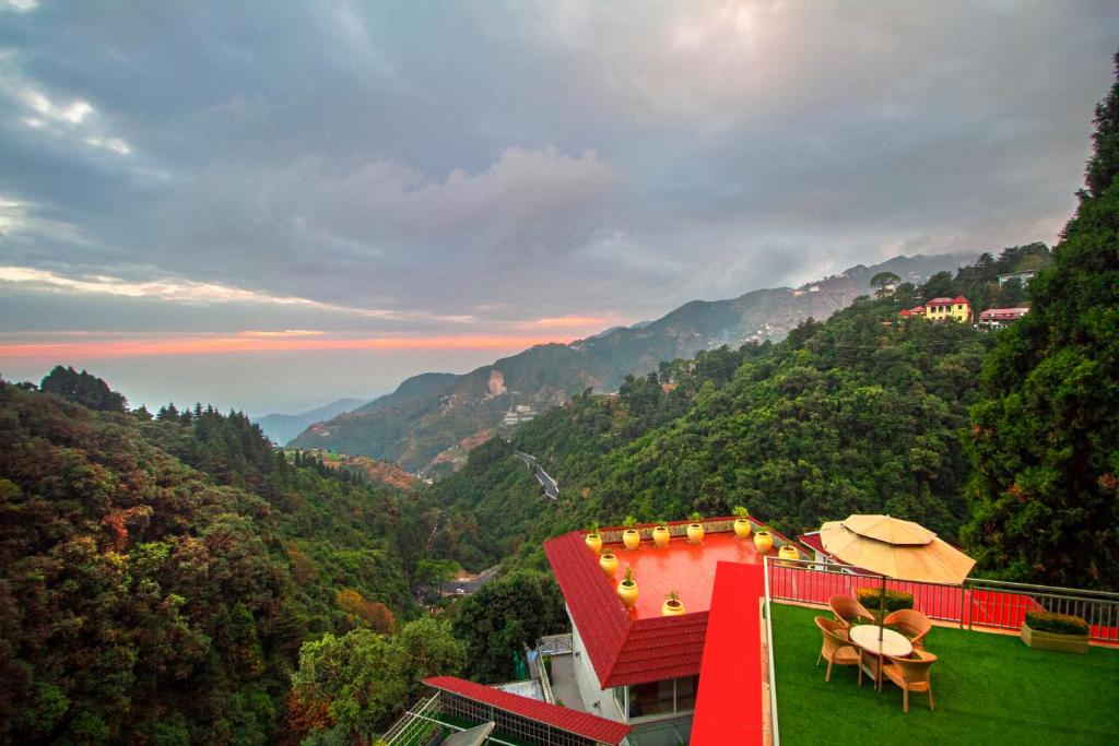 a house with a red roof with a view of mountains at Yog Wellness Resort & Spa By Amritara in Mussoorie