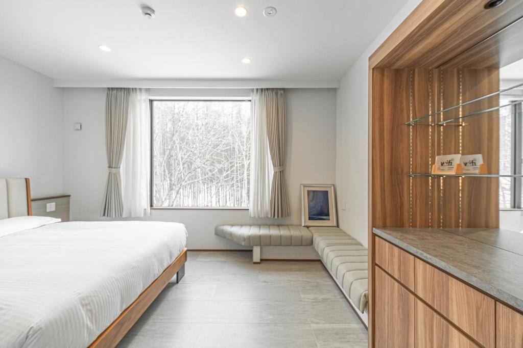 um quarto com uma cama, um sofá e uma janela em Villa Yin Niseko em Niseko