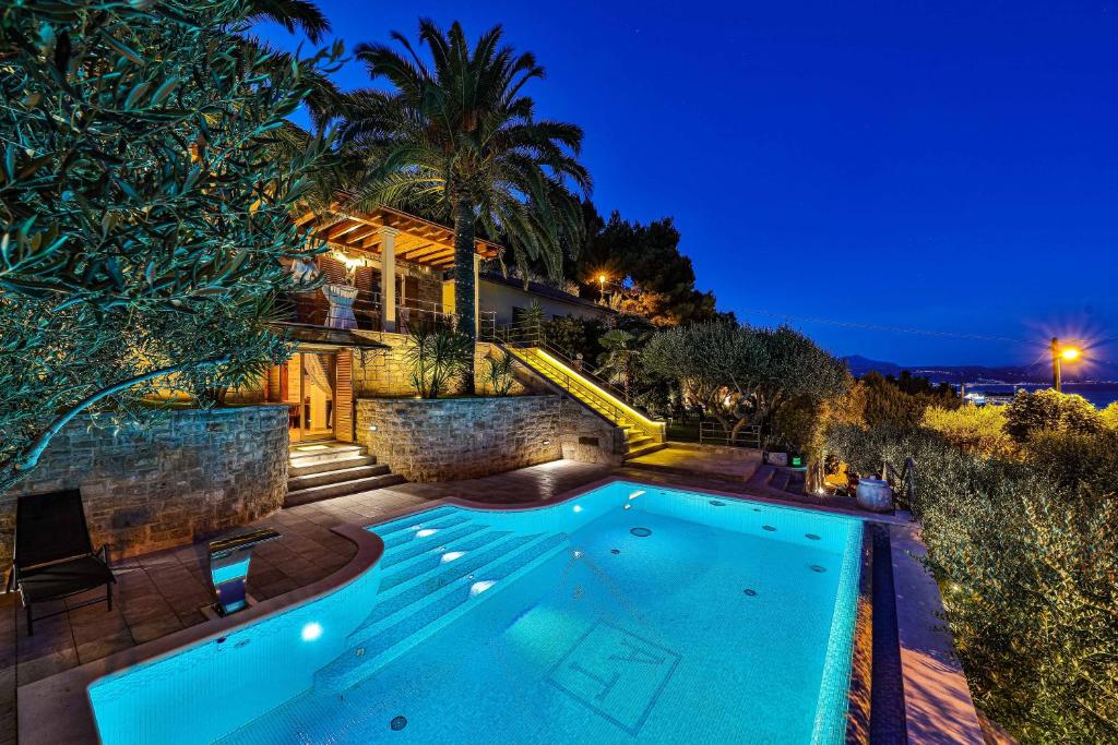 a swimming pool in front of a house at night at Villa Tomislav in Split
