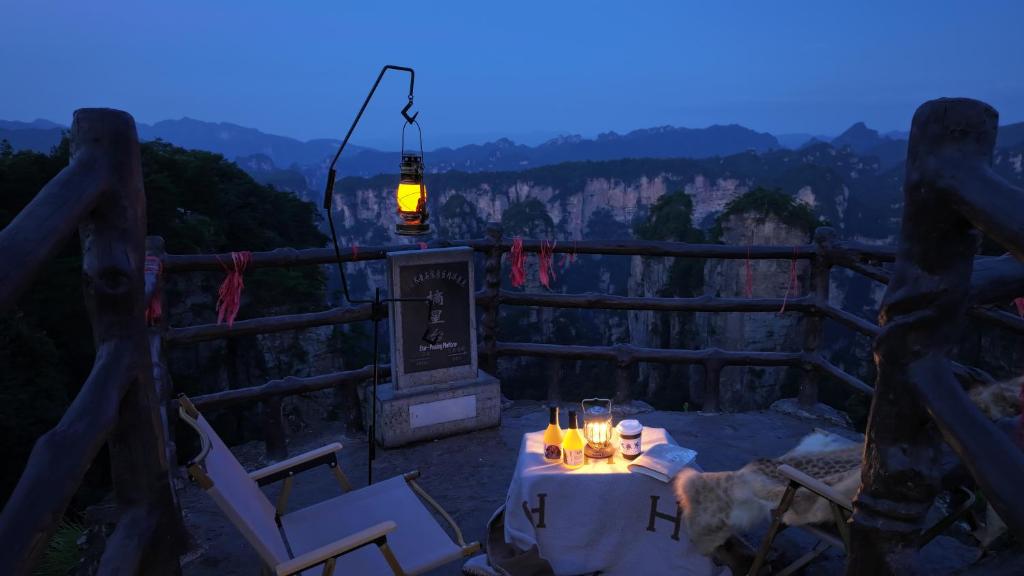 Yoba Boutique Hotel في تشانغجياجيه: طاوله مع كراسي واضاءه على الجبل