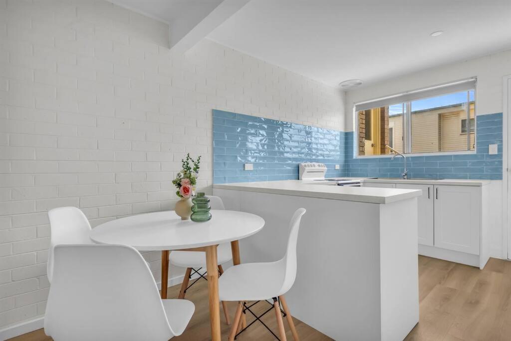 a kitchen with a white table and white chairs at Marine Court - Unit 6 in Merimbula