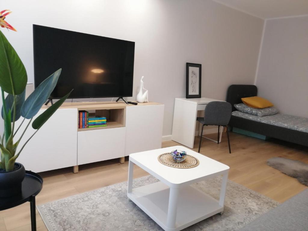 een woonkamer met een tv en een witte tafel bij Apartament - Classic Olszowa in Włocławek