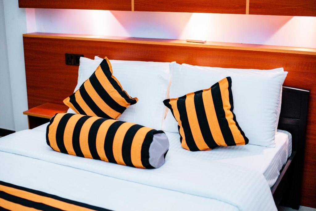 a bed with black and yellow striped pillows on it at Villa Andaz in Negombo