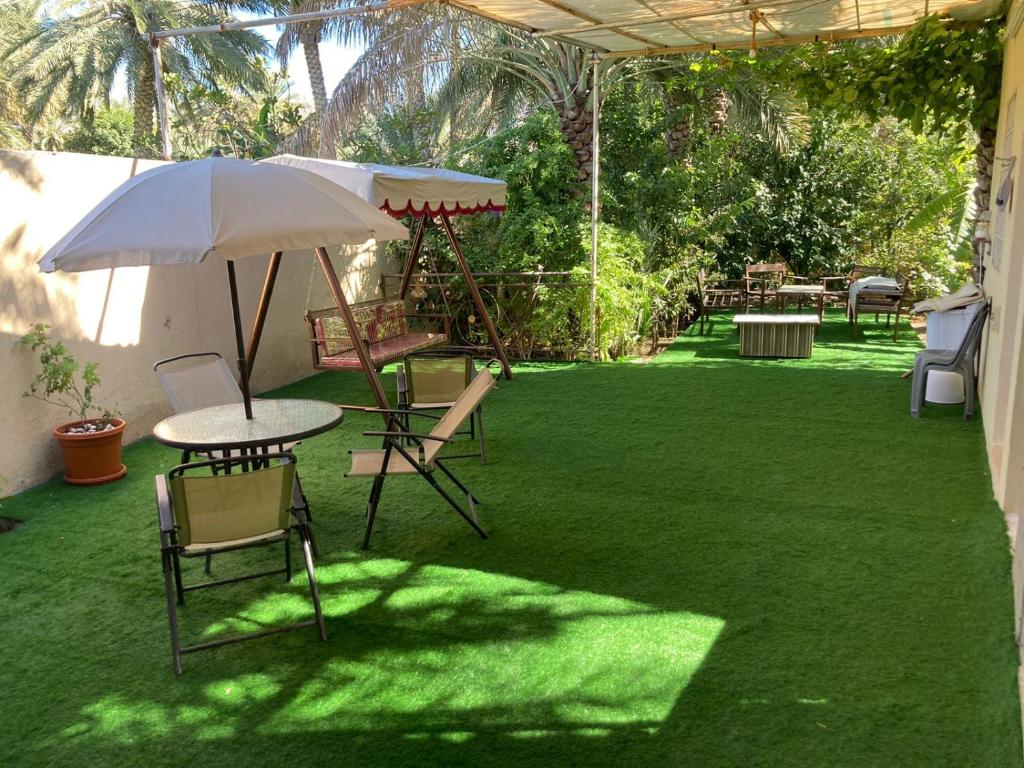 un patio con mesa, sillas y sombrilla en Reef Alhamra en Al Ḩamrāʼ