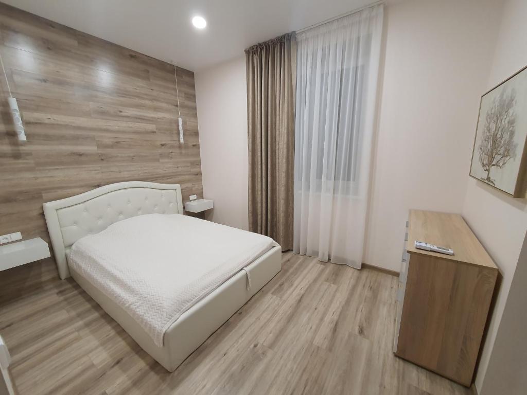 a bedroom with a white bed and a wooden wall at Apartamentai Harmonija in Akmenė