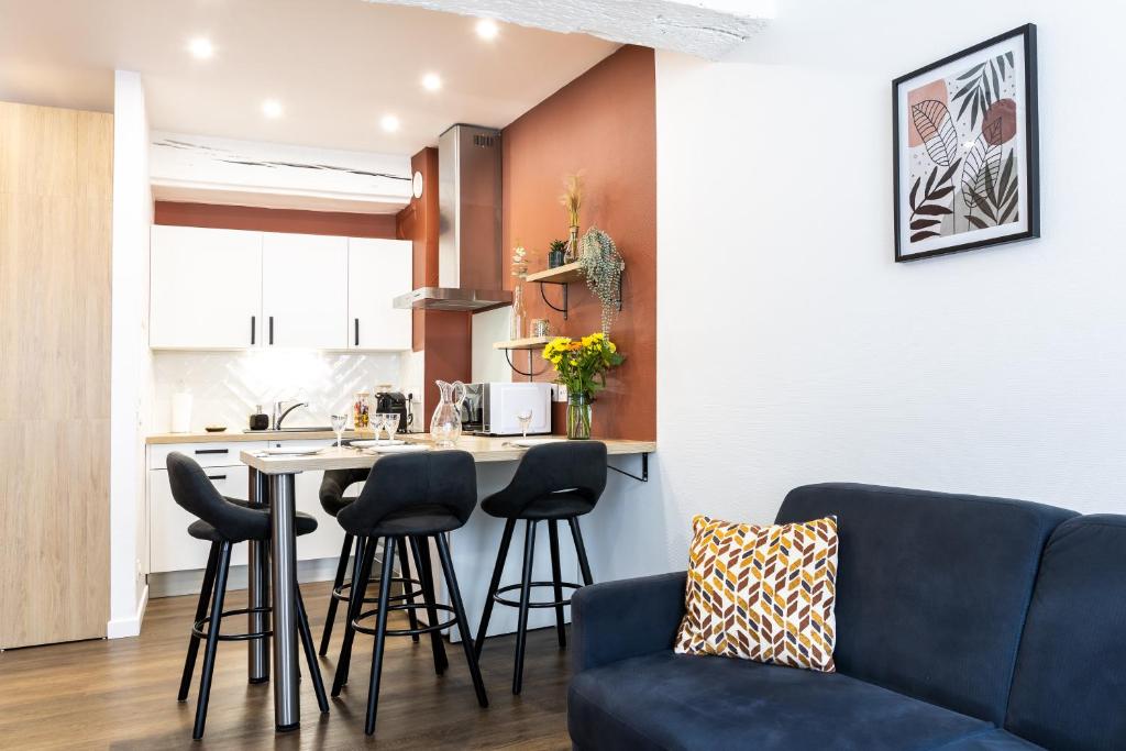 uma sala de estar com um sofá azul e uma cozinha em Le Constantin - Ecrin chaleureux & confortable, centre-ville à 2 pas em Provins