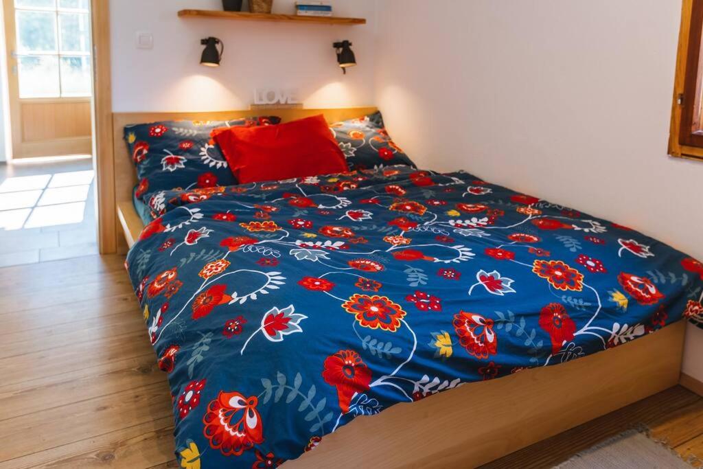 1 cama con edredón azul y almohada roja en Pr'Kovač 2 /Perfect stay for 2, en Bohinjska Bela