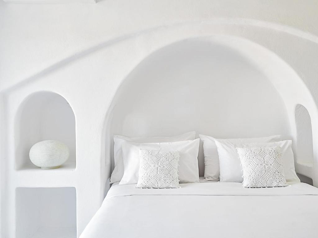 a white bedroom with a white bed with white pillows at Mykonos Lolita, A Grecotel Resort to Live in Agios Sostis Mykonos