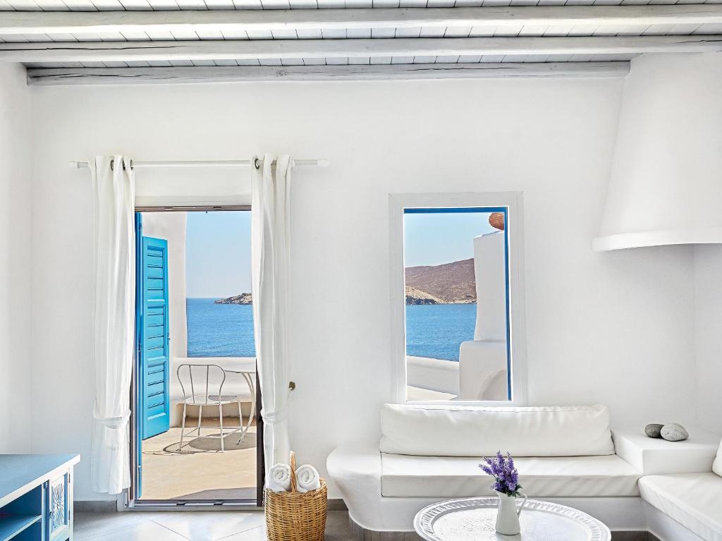 a white living room with a view of the ocean at Mykonos Lolita, A Grecotel Resort to Live in Agios Sostis Mykonos