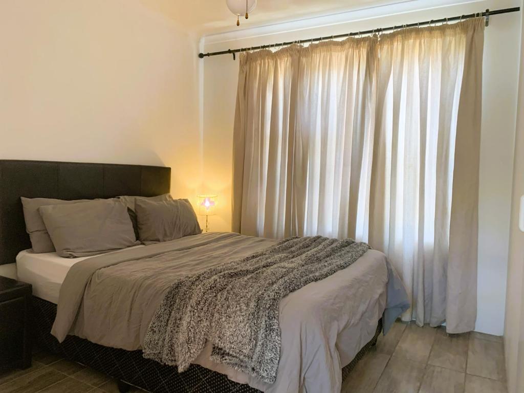 a bedroom with a bed and a window with curtains at Apartment with garden, and garage in Cape Town
