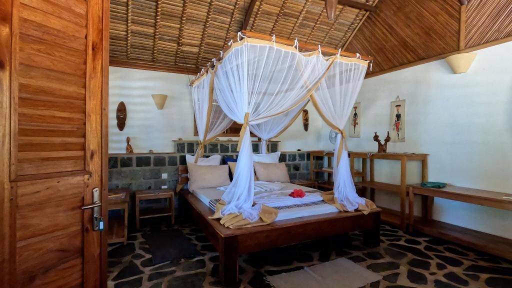 a bedroom with a canopy bed with white curtains at Ravo Ravo Resort Nosy Be in Antafondro