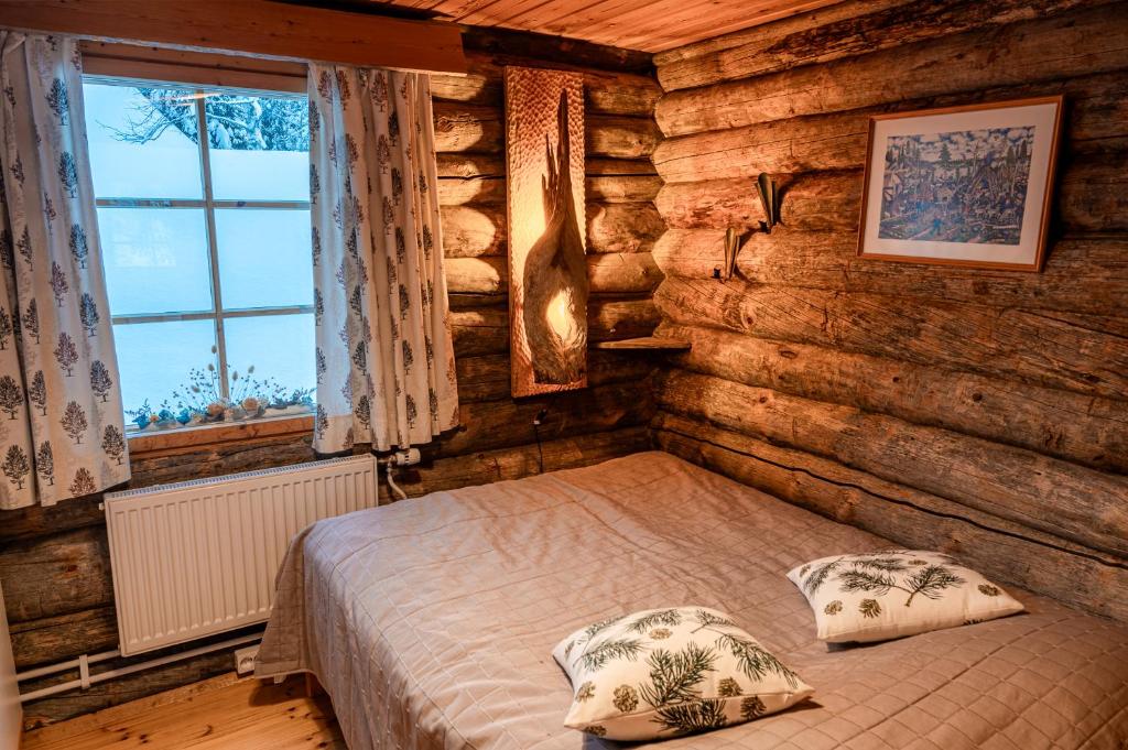 - une chambre avec un lit dans une cabane en rondins dans l'établissement Hillankukka, à Äkäslompolo