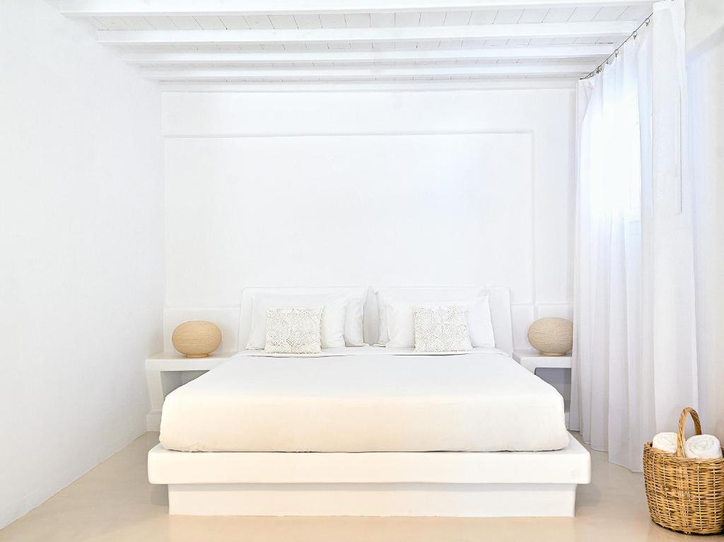 a white bedroom with a white bed and a window at Mykonos Lolita, A Grecotel Resort to Live in Agios Sostis Mykonos
