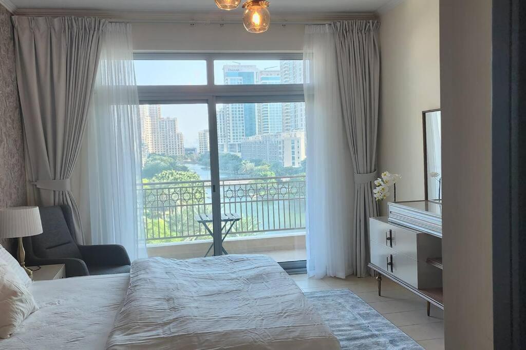a bedroom with a bed and a large window at Lake View The Greens & Views in Dubai