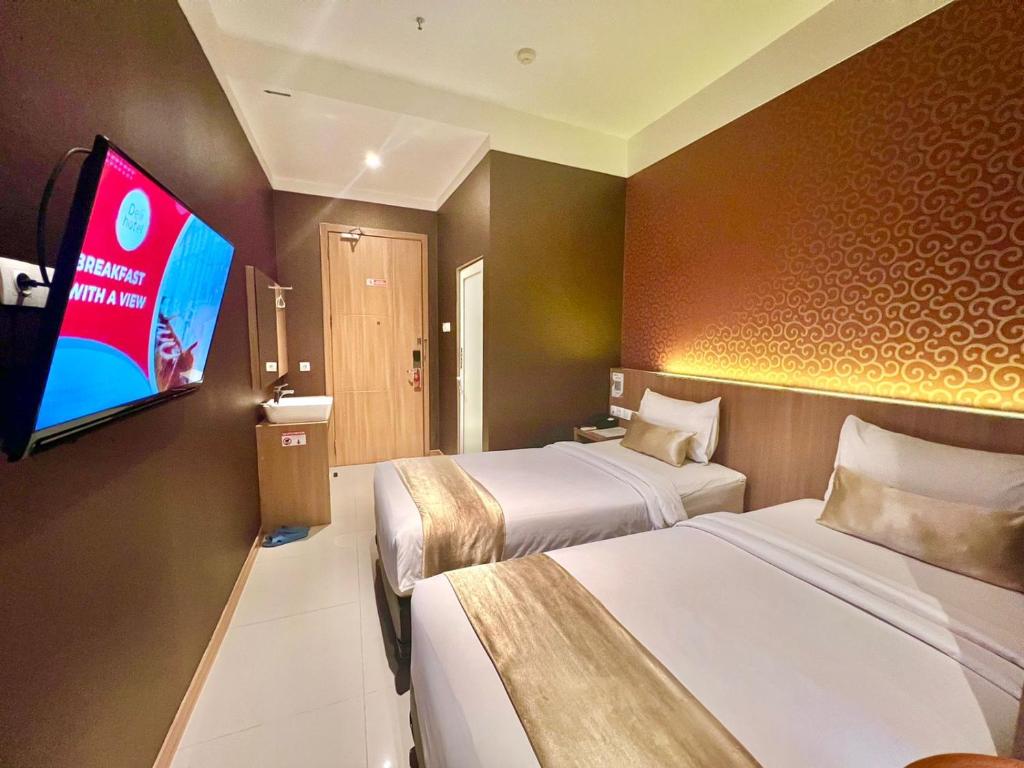 um quarto de hotel com duas camas e uma televisão de ecrã plano em Deli Hotel em Medan