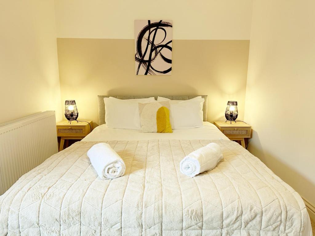 a bedroom with a large white bed with towels on it at Cotswold's Large 4 bed house-Sleeps 10-Free Parking-Wifi 