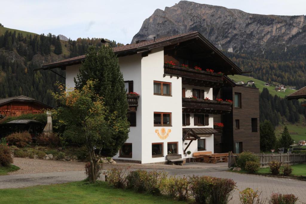 a large white building with a mountain in the background at Garni Tramans in Selva di Val Gardena