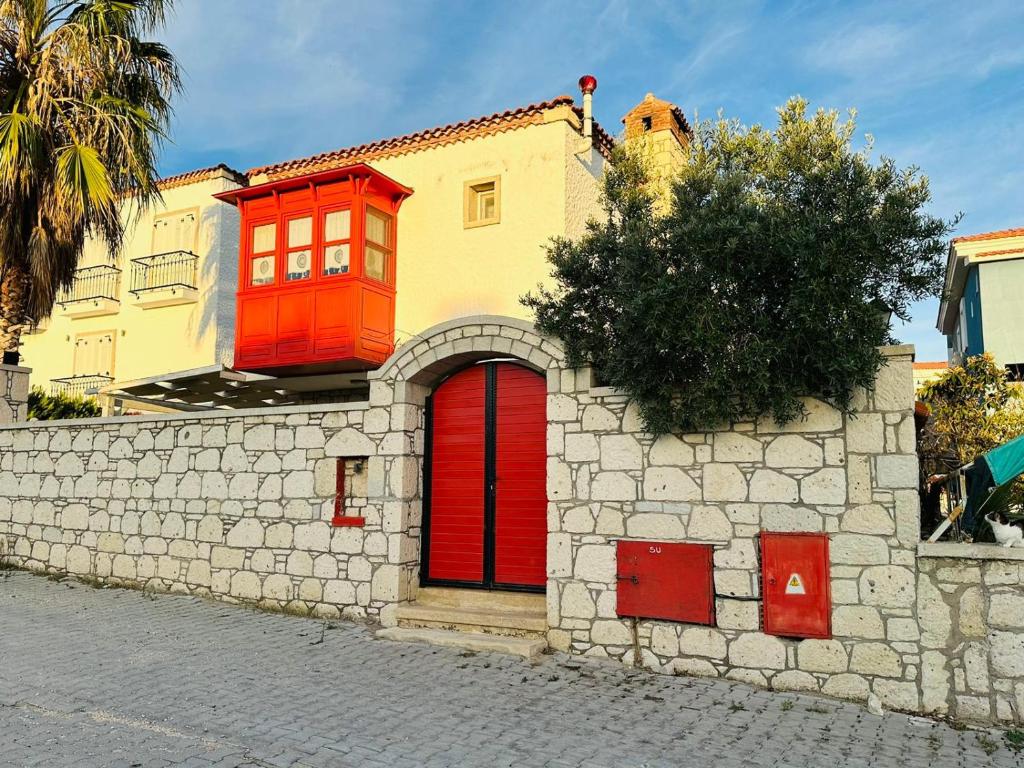 a house with red doors on a stone wall at Evalacati - Villa Palma-Tamamen Müstakil Villa in Cesme