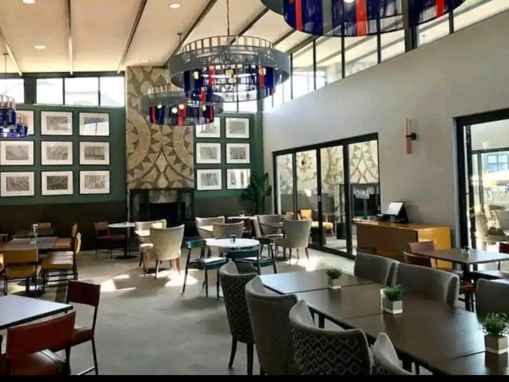 a restaurant with tables and chairs and a fireplace at URlyfstyle Kikuyu Escape Waterfall Mall of Africa in Midrand