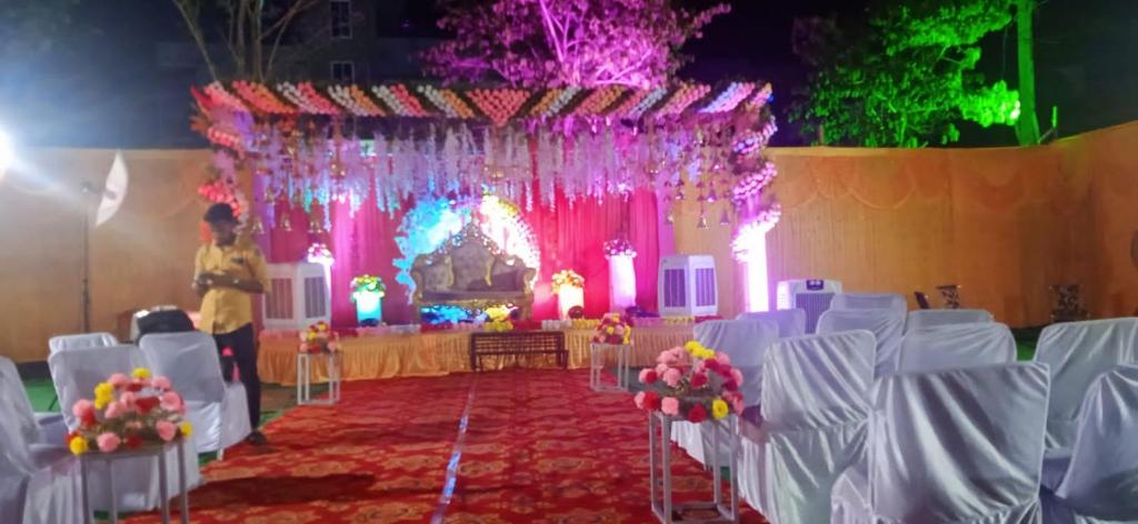 un salón de banquetes con sillas blancas y un altar con flores en Oak Villa, en Ranchi