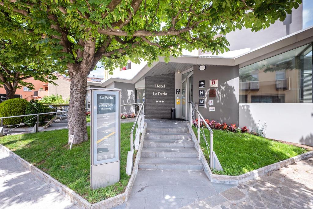 un bâtiment avec un arbre et des escaliers en face de celui-ci dans l'établissement HOTEL LA PERLA, à Olot