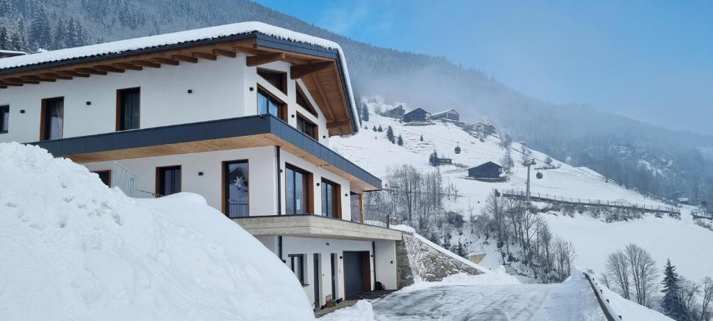 um edifício sobre uma montanha coberta de neve com telhados cobertos de neve em Apartment Talblick em Bramberg am Wildkogel