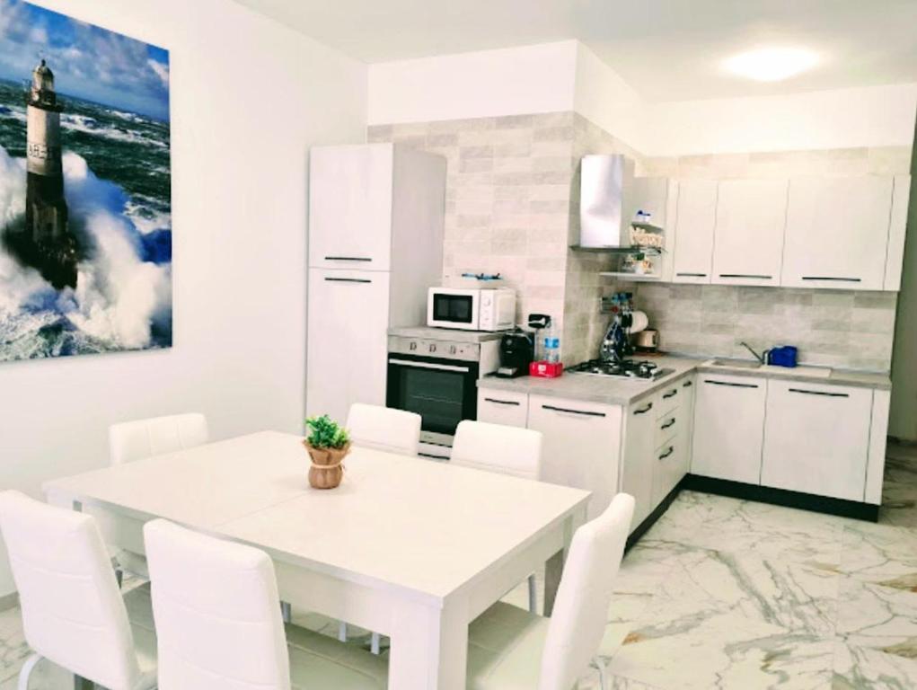 Hotel Elegante trilocale Casinò di Sanremo, a white kitchen with a white table and white appliances at Elegante trilocale Casinò di Sanremo in Sanremo