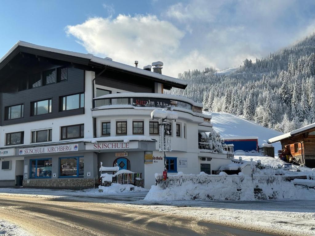 Un grand bâtiment blanc avec de la neige au sol dans l'établissement Apartments Max & Moritz, à Kirchberg in Tirol