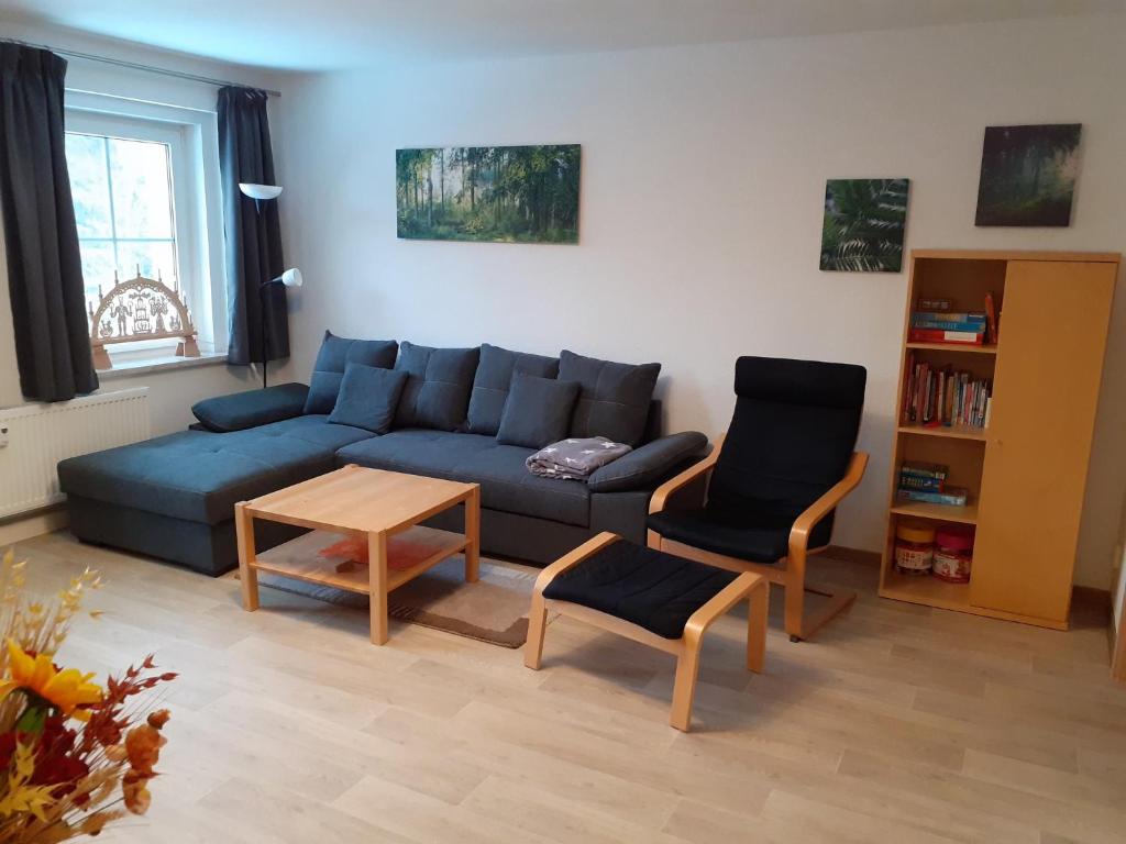 ein Wohnzimmer mit einem blauen Sofa und 2 Stühlen in der Unterkunft Ferienwohnung Zern in Johanngeorgenstadt