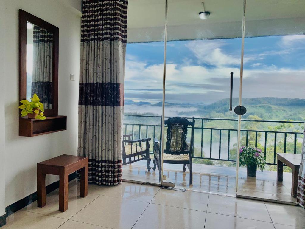 a room with a balcony with a view of the ocean at The Station Lodge in Haputale