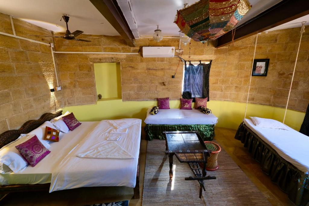 a room with two beds and a chair at Saffron Homestay in Jaisalmer