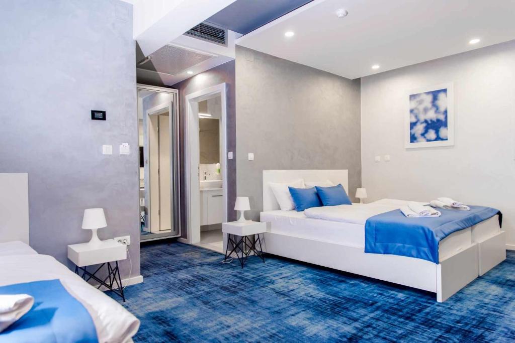 a bedroom with two beds and a blue carpet at Hotel Biss in Zenica
