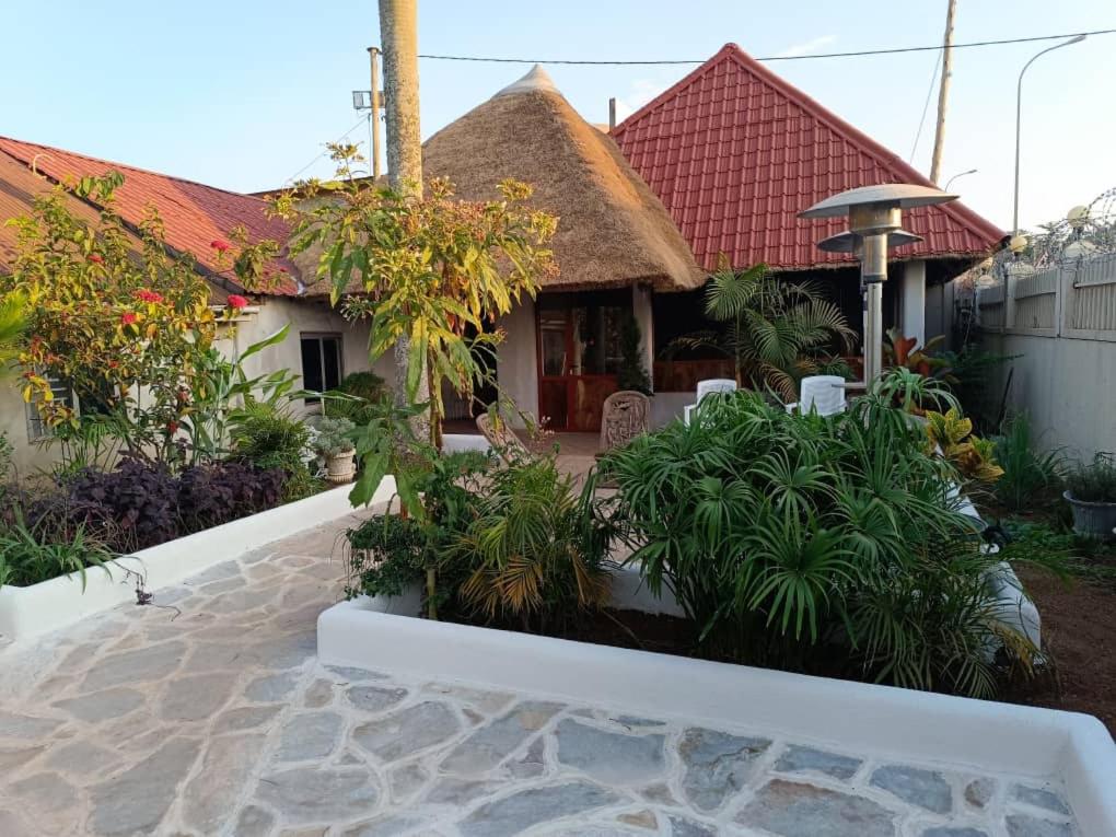 a house with a thatched roof and a patio at Mia Safari Lodge and Restaurant in Entebbe