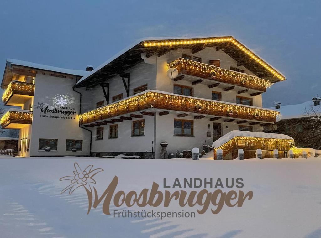 シュテークにあるLandhaus Moosbruggerの雪面のクリスマスライトで覆われた建物