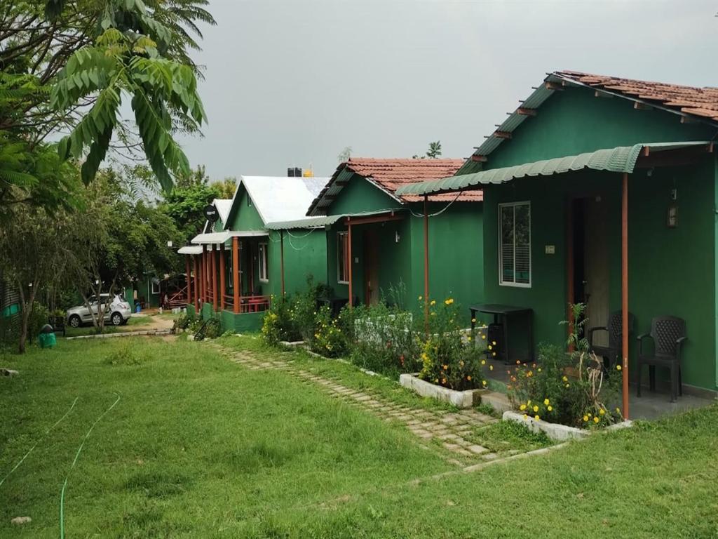 una casa verde con un patio delante en The Wild Farms By Gwestai en Masinagudi