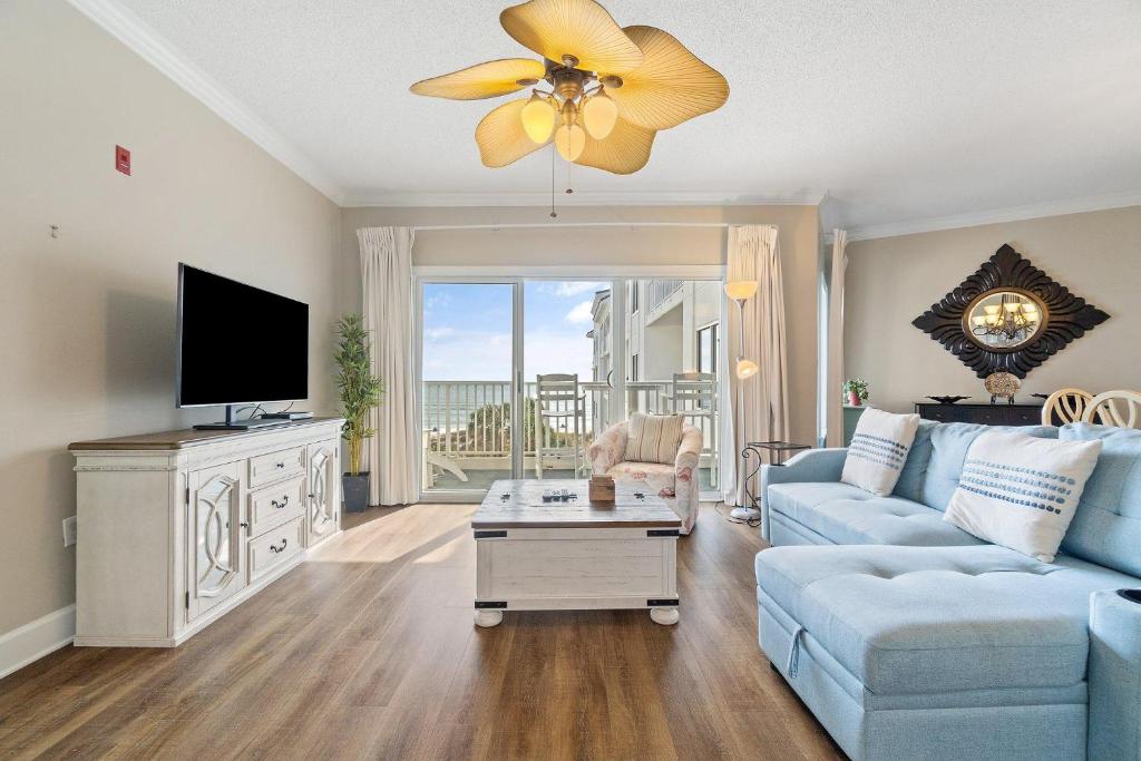 uma sala de estar com um sofá azul e uma televisão em Palm Beach D45 em Gulf Shores