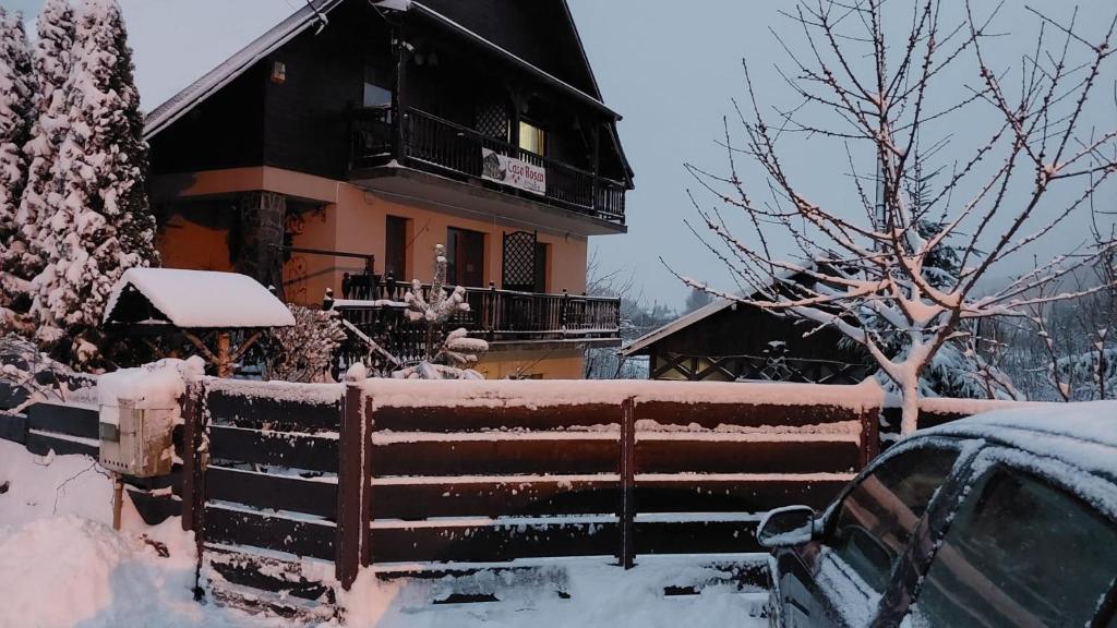 una casa con una valla cubierta de nieve en Casa Rosca Busteni, en Buşteni