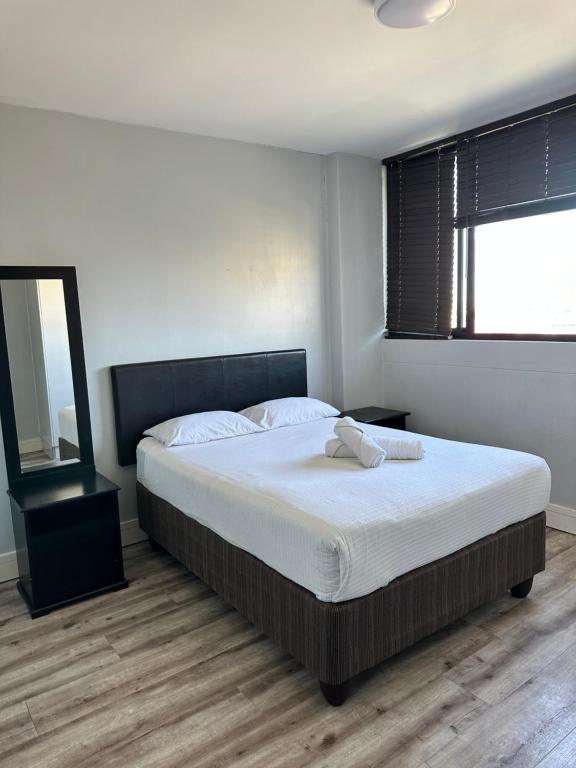 una camera da letto con un grande letto con lenzuola bianche e una finestra di Sweet Cozy CBD apartment a Windhoek