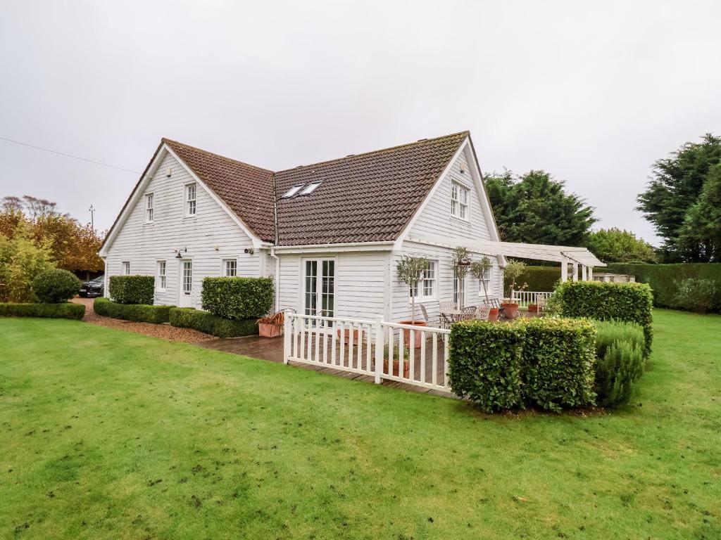 a white house with a fence in a yard at Lampland House in Southwold