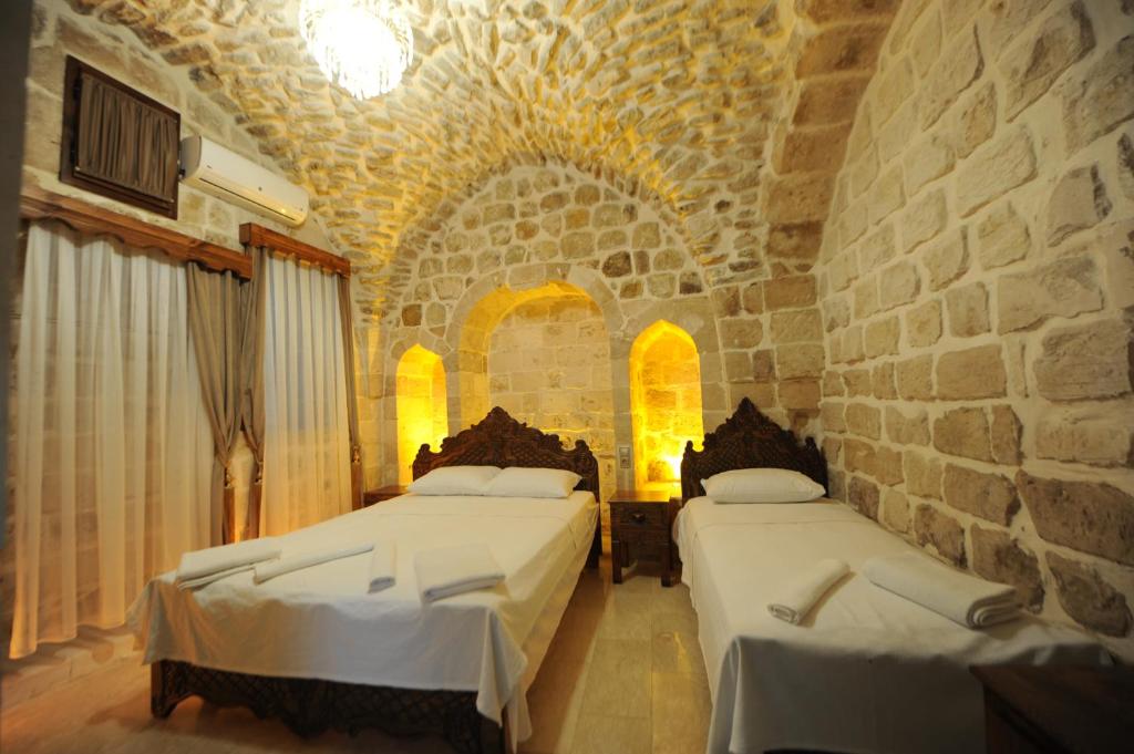 1 Schlafzimmer mit 2 Betten und einer Steinmauer in der Unterkunft ARTUKHAN BUTİK HOTEL in Mardin
