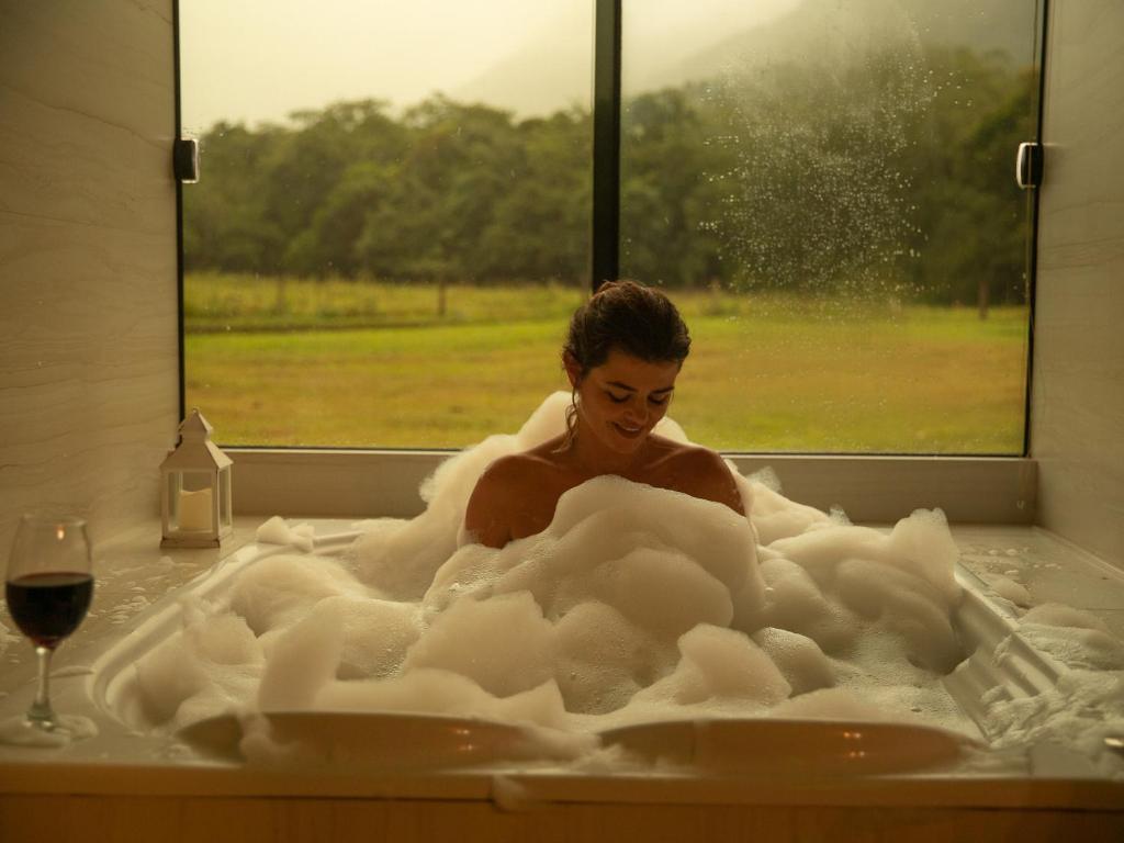 a woman is sitting in a bathtub filled with foam at Pousada Índios Coroados in Praia Grande