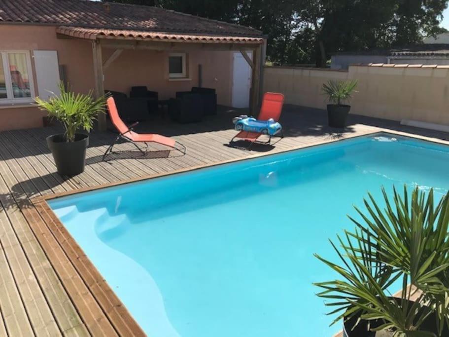 ein großer Pool mit zwei Stühlen und ein Haus in der Unterkunft La Roselière - Villa proche mer * Au calme in Fouras