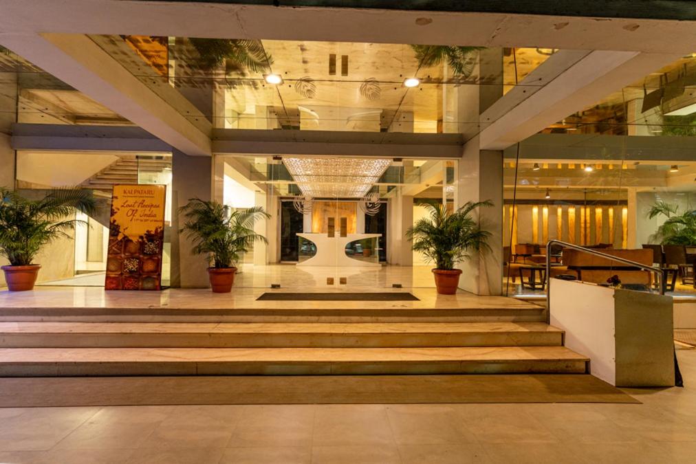 a lobby with stairs and potted plants in a building at Hotel Hardeo in Nagpur
