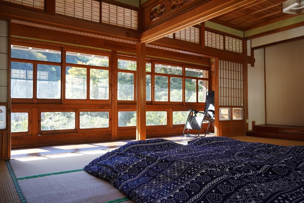 a bedroom with a bed in a room with windows at TOSAYAMA BASE 清流沿いの里山　古民家貸切　高知市街地より車で約20分 in Kochi