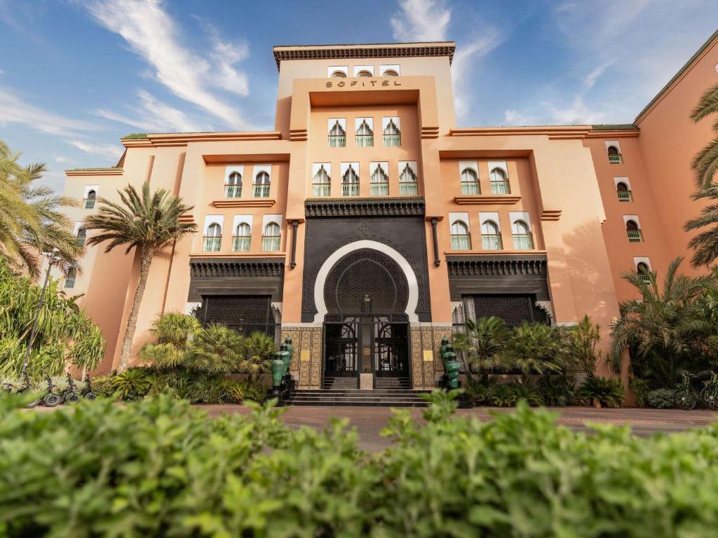 un bâtiment avec des palmiers en face de celui-ci dans l'établissement Sofitel Marrakech Palais Imperial And Spa, à Marrakech