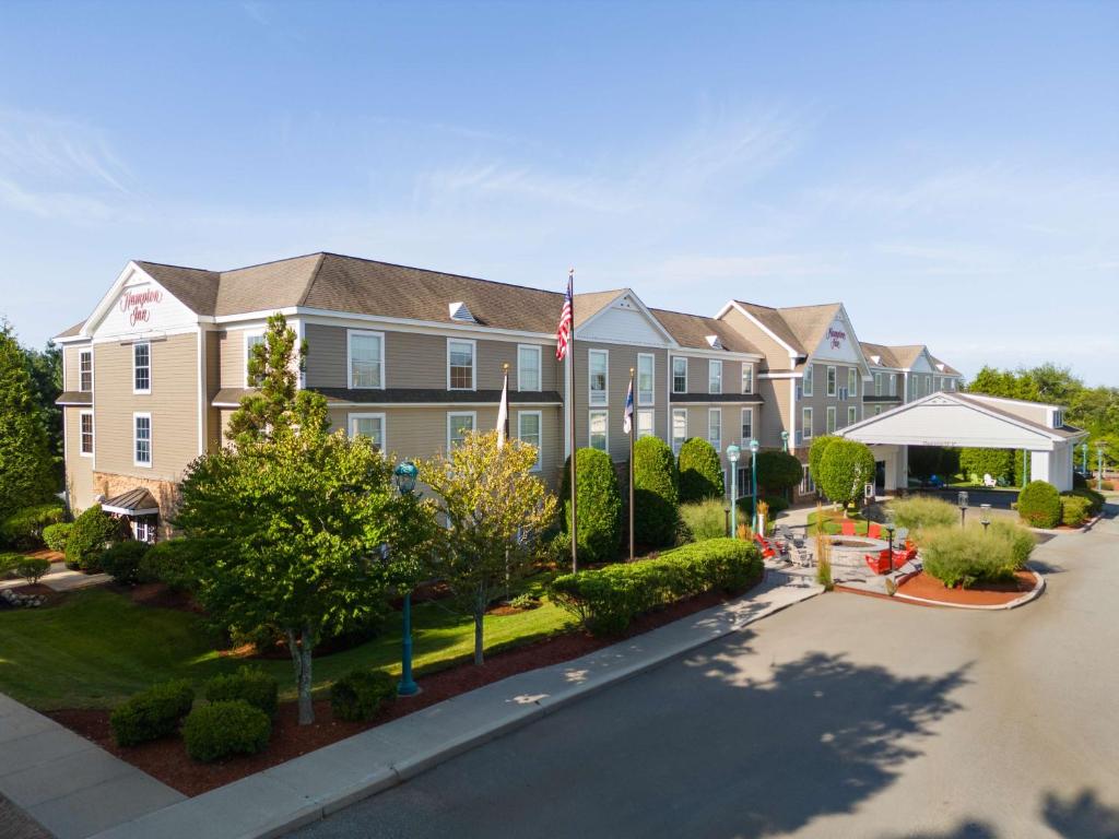 Um edifício de apartamentos com uma bandeira americana à frente. em Hampton Inn South Kingstown - Newport Area em South Kingstown