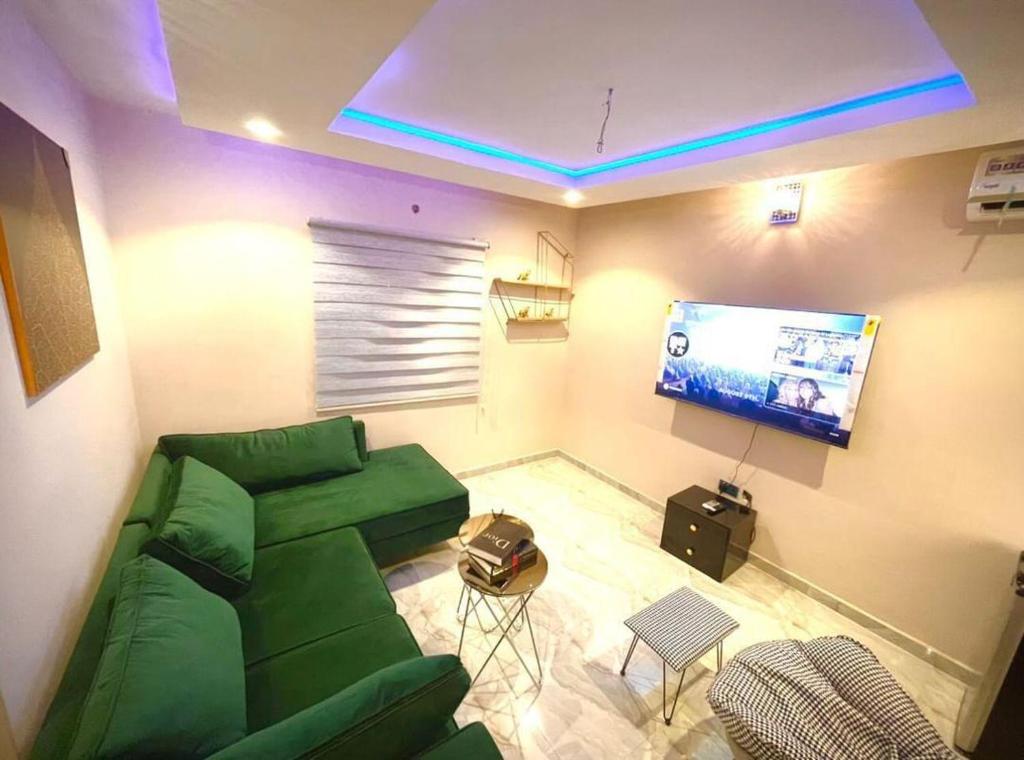 sala de estar con sofá verde y TV de pantalla plana en Blueprint Apartment, en Akure