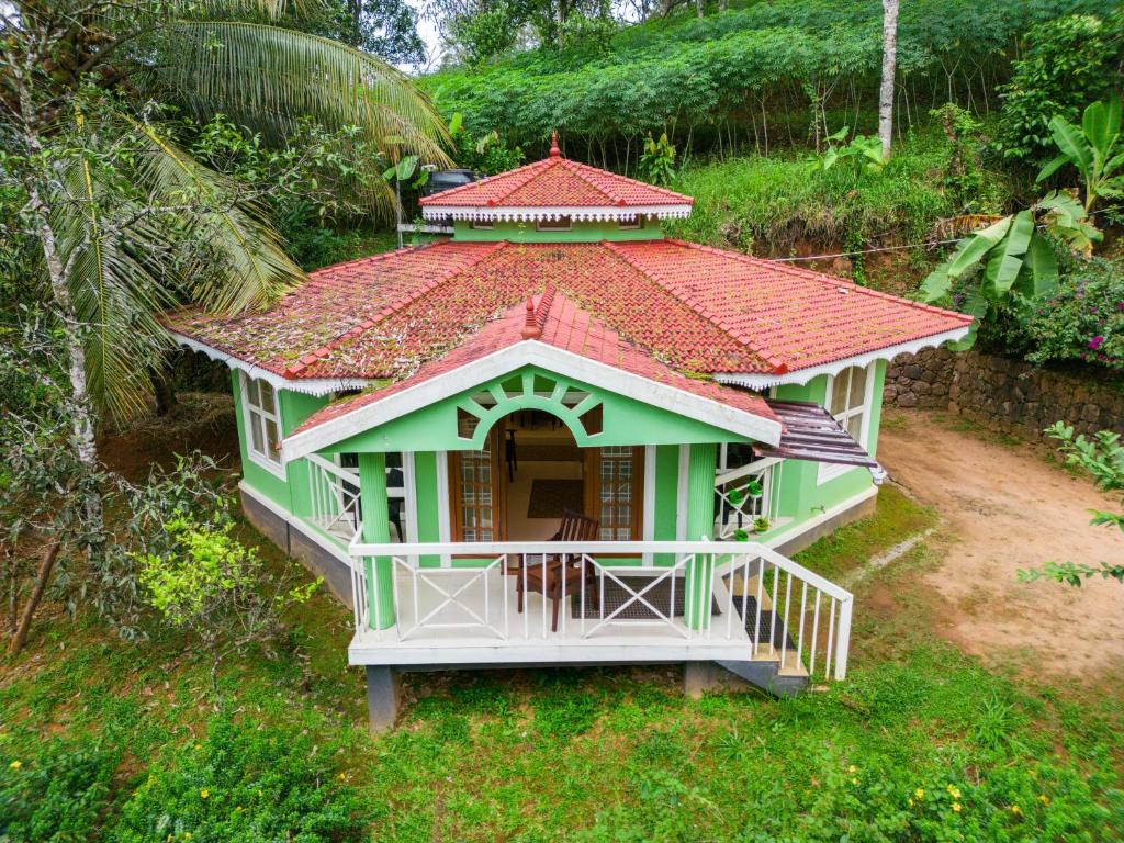 uma pequena casa verde com um telhado vermelho em Nature Routes Cottage em Munnar